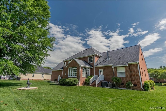 back of property with a lawn, central air condition unit, and brick siding