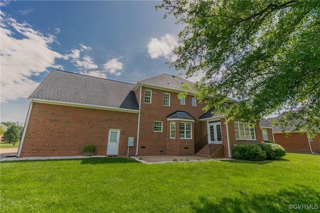 rear view of property featuring a yard, brick siding, and a patio area