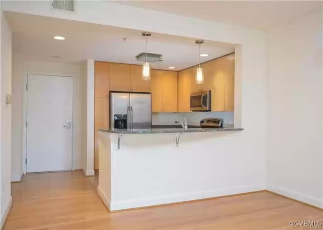 kitchen featuring dark countertops, stainless steel appliances, light wood finished floors, baseboards, and visible vents