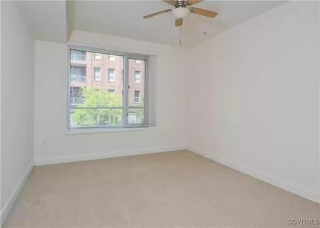 empty room featuring a ceiling fan, light carpet, a healthy amount of sunlight, and baseboards