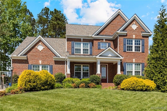 craftsman inspired home featuring roof with shingles, covered porch, a front lawn, and brick siding