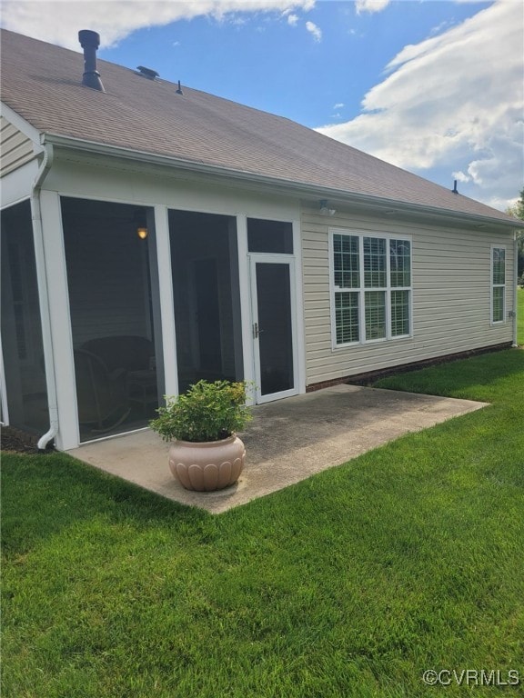 back of house with roof with shingles, a patio, and a yard