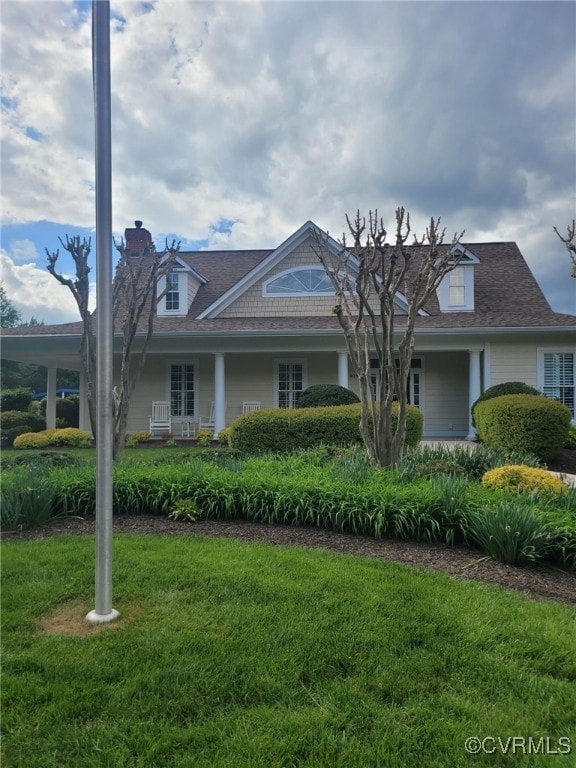 view of front facade featuring roof with shingles, a chimney, and a front lawn