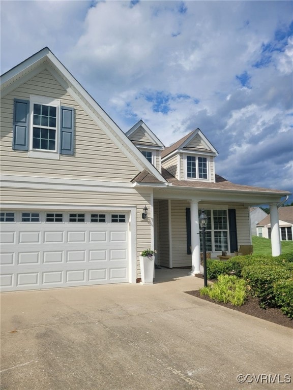 traditional-style home featuring a garage, covered porch, and concrete driveway
