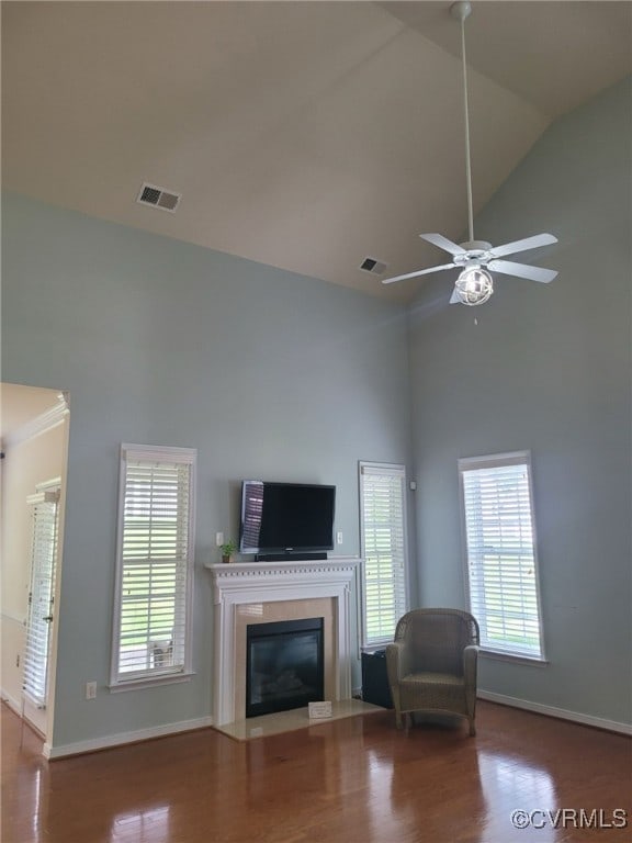 living room featuring visible vents, wood finished floors, baseboards, high vaulted ceiling, and a fireplace with flush hearth
