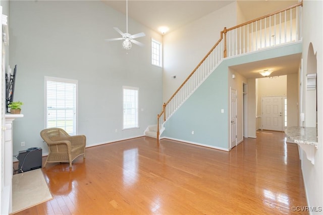 7516 Shadow Lands Ct, Mechanicsville, VA 23111 - unfurnished living room featuring a towering ceiling, ceiling fan, light wood finished floors, stairs, and baseboards