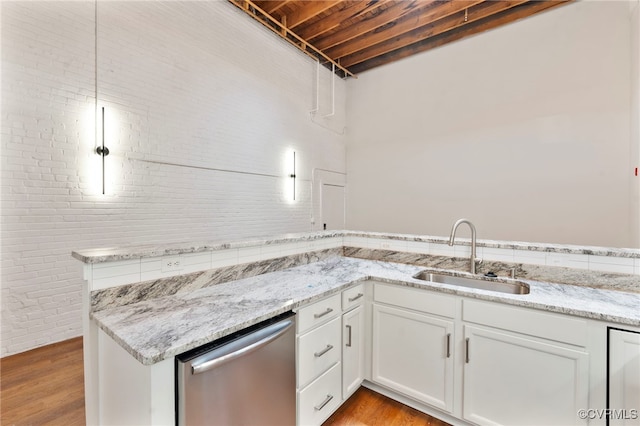 kitchen featuring white cabinets, light stone counters, a sink, dishwasher, and light wood-type flooring