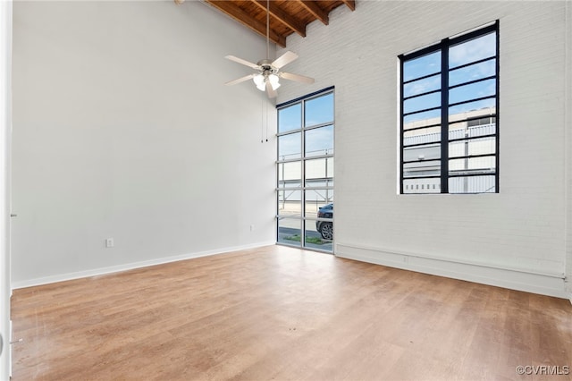 spare room featuring high vaulted ceiling, baseboards, beam ceiling, and wood finished floors