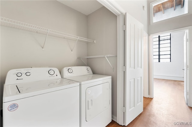 laundry room featuring laundry area, light wood finished floors, a healthy amount of sunlight, and washing machine and clothes dryer