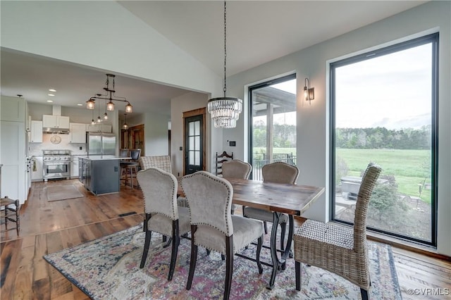 dining space featuring recessed lighting, wood finished floors, lofted ceiling, and a notable chandelier