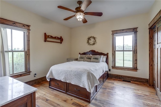 bedroom featuring baseboards, multiple windows, and light wood finished floors