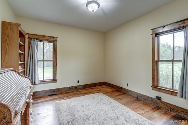 interior space featuring visible vents, plenty of natural light, baseboards, and wood finished floors
