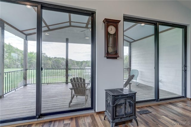 entryway with wood finished floors, a wood stove, and a wealth of natural light