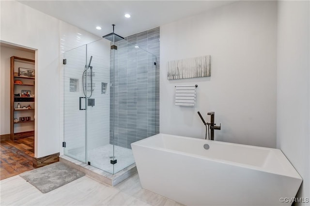 full bath with recessed lighting, a shower stall, a soaking tub, and wood finished floors