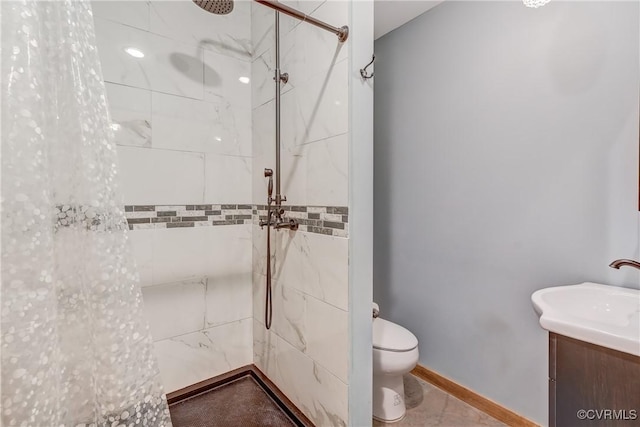 full bathroom with a tile shower, toilet, vanity, and baseboards
