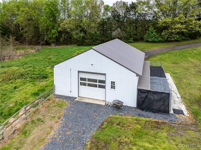 view of outbuilding with fence, gravel driveway, an outdoor structure, and a garage