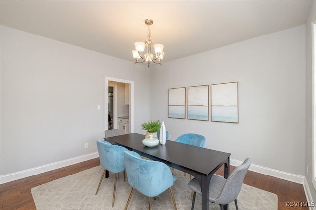 dining area with baseboards, a notable chandelier, and wood finished floors