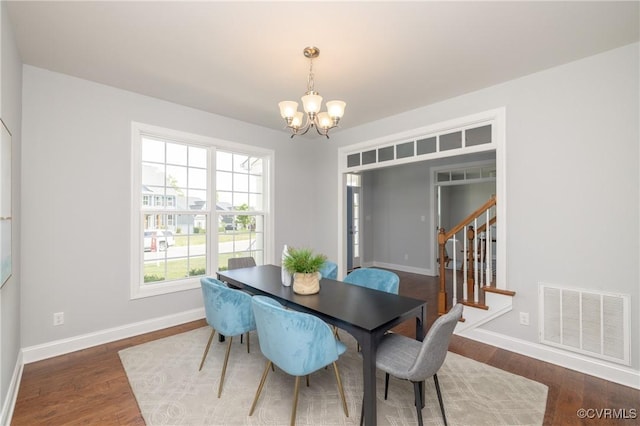 dining room featuring visible vents, baseboards, wood finished floors, and a chandelier
