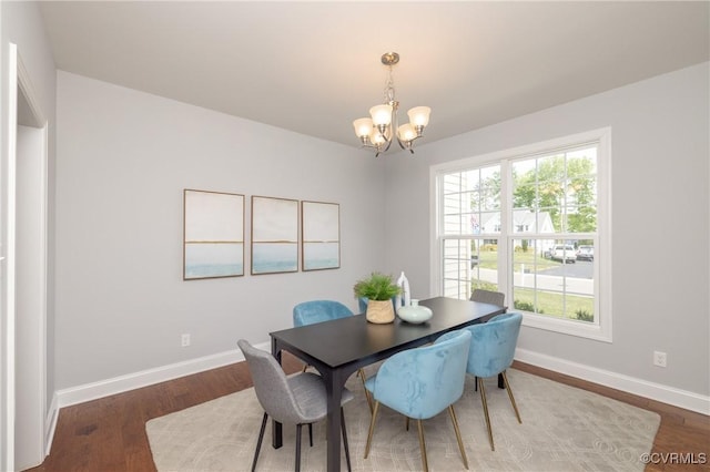 dining space featuring baseboards, a notable chandelier, and wood finished floors