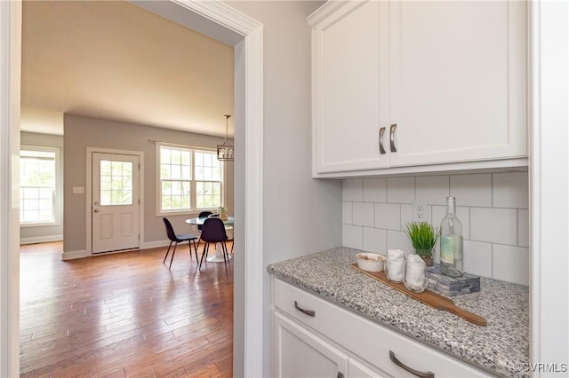bar featuring baseboards, light wood-type flooring, and tasteful backsplash