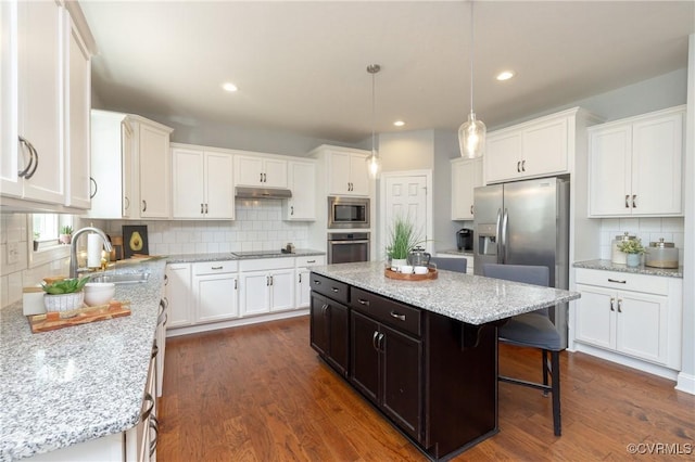 kitchen with appliances with stainless steel finishes, a sink, white cabinetry, backsplash, and under cabinet range hood