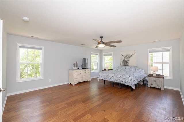 bedroom featuring baseboards, ceiling fan, multiple windows, and wood finished floors
