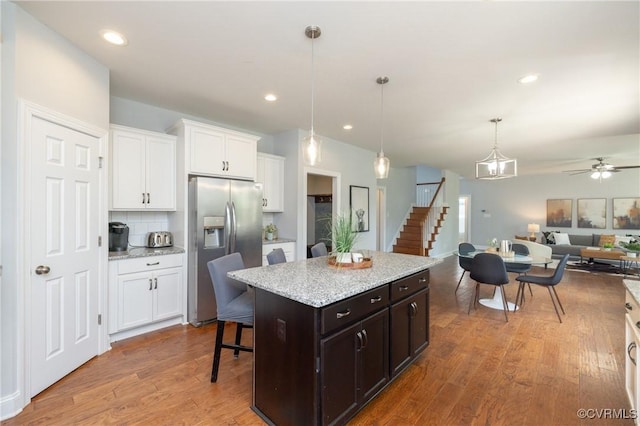 kitchen featuring open floor plan, white cabinets, stainless steel fridge with ice dispenser, a ceiling fan, and hanging light fixtures