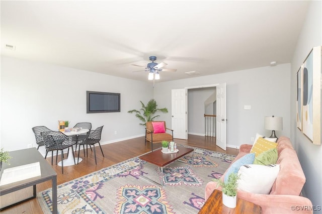 living room with baseboards, ceiling fan, and wood finished floors