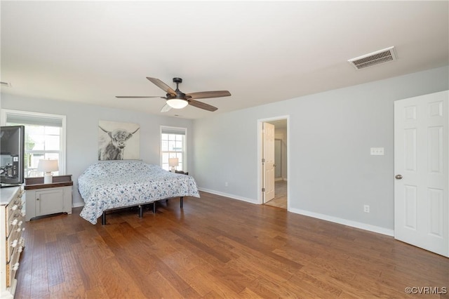bedroom with a ceiling fan, baseboards, visible vents, and wood finished floors