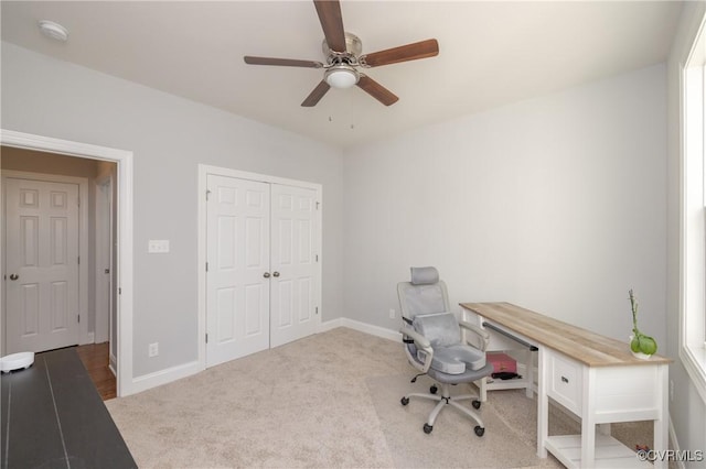 carpeted office space with baseboards and ceiling fan