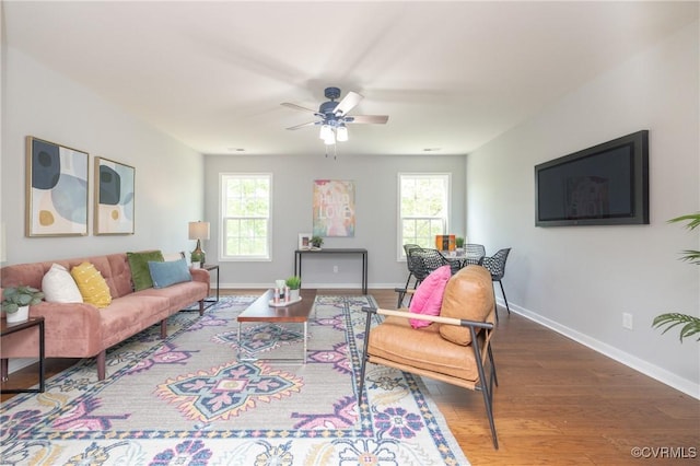 living room with baseboards, plenty of natural light, a ceiling fan, and wood finished floors