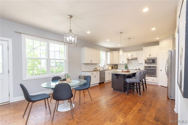 dining room with a healthy amount of sunlight, dark wood-style flooring, and a notable chandelier