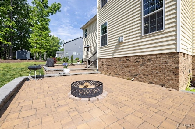 view of patio with an outbuilding, a fire pit, and a shed