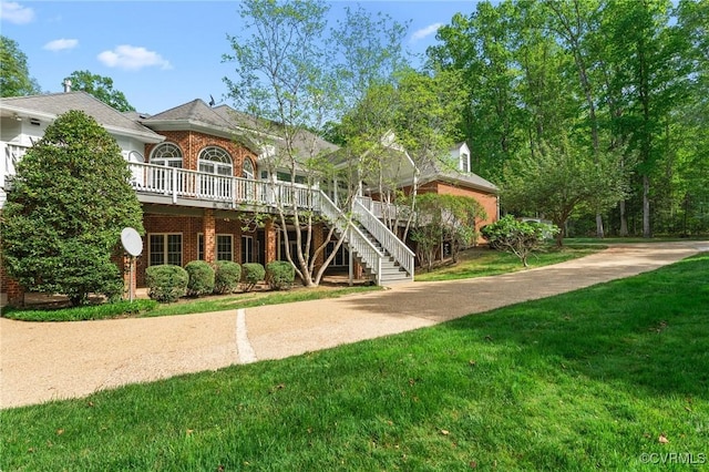 view of front of property featuring brick siding, a front yard, and stairs