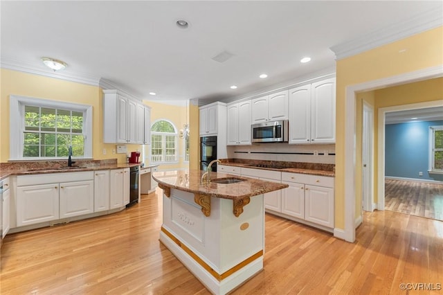 kitchen with white cabinetry, black appliances, stone counters, and a sink
