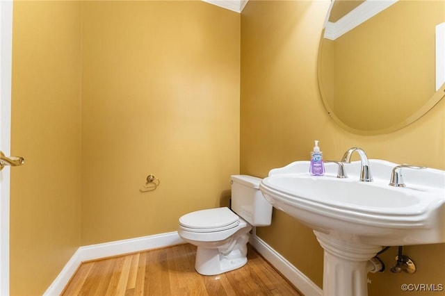 half bath featuring wood finished floors, toilet, and baseboards
