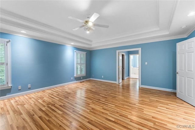 unfurnished room featuring crown molding, light wood finished floors, a ceiling fan, and a raised ceiling