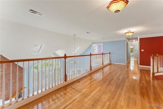 interior space with wood finished floors, visible vents, ornamental molding, and baseboards