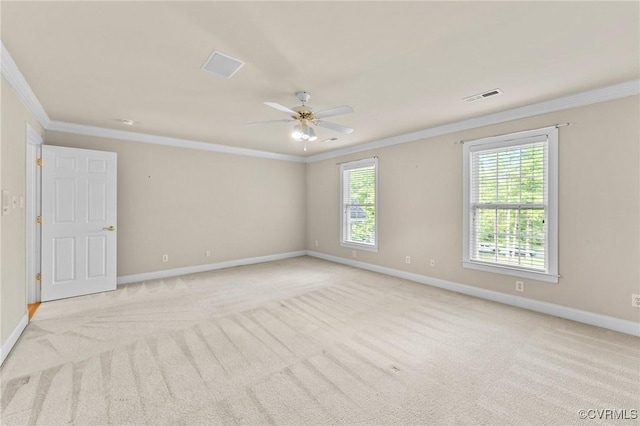 empty room with light colored carpet, ornamental molding, ceiling fan, baseboards, and visible vents