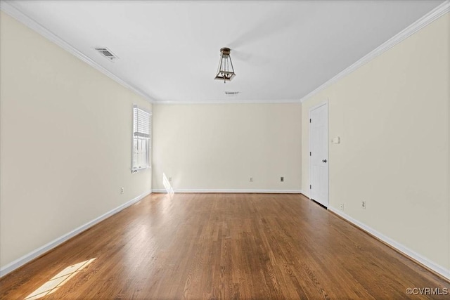 empty room with visible vents, ornamental molding, baseboards, and wood finished floors