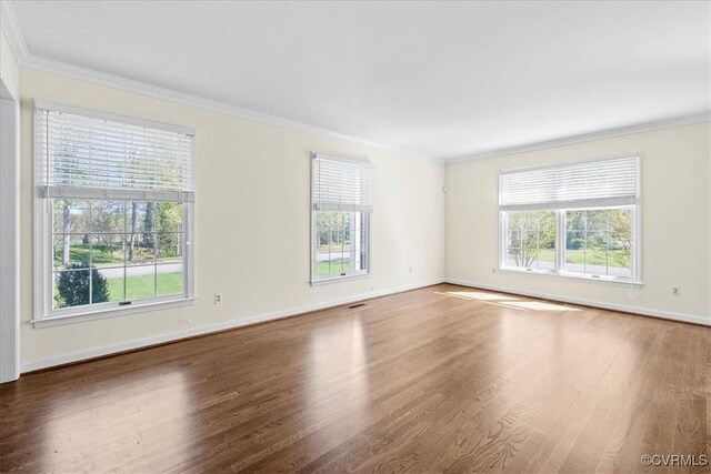 unfurnished room featuring visible vents, baseboards, crown molding, and wood finished floors