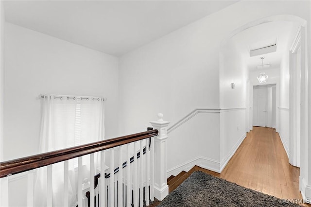 corridor featuring an upstairs landing, light wood-style floors, and baseboards