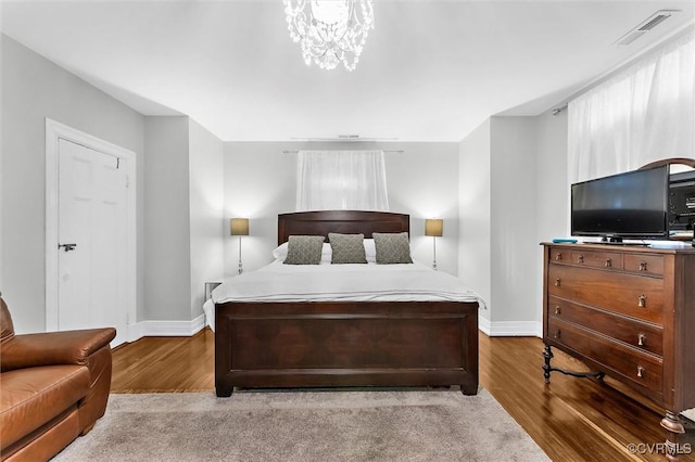 bedroom featuring baseboards, wood finished floors, and a chandelier