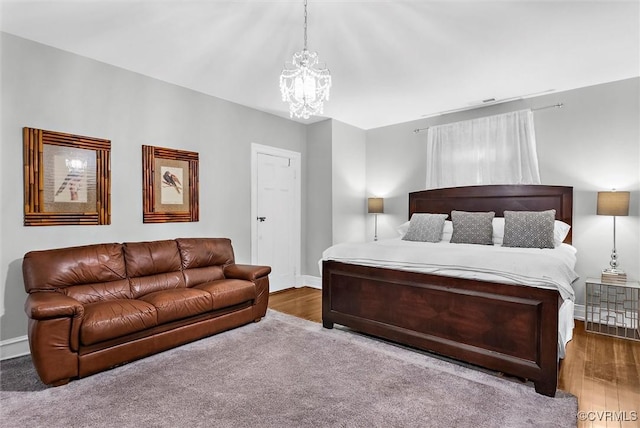 bedroom featuring a chandelier, baseboards, and wood finished floors
