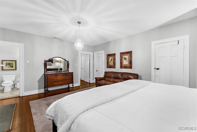 bedroom with hardwood / wood-style flooring, a chandelier, baseboards, and ensuite bath