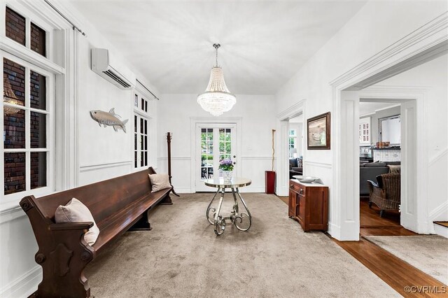 living area featuring an AC wall unit, a chandelier, a decorative wall, and wood finished floors