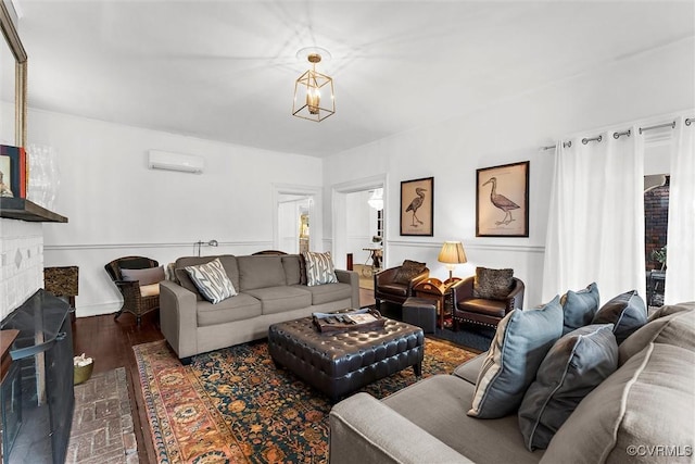 living area featuring a wall mounted AC, wood finished floors, and a brick fireplace