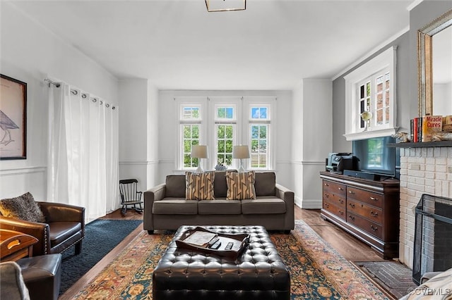 living room featuring a brick fireplace and wood finished floors