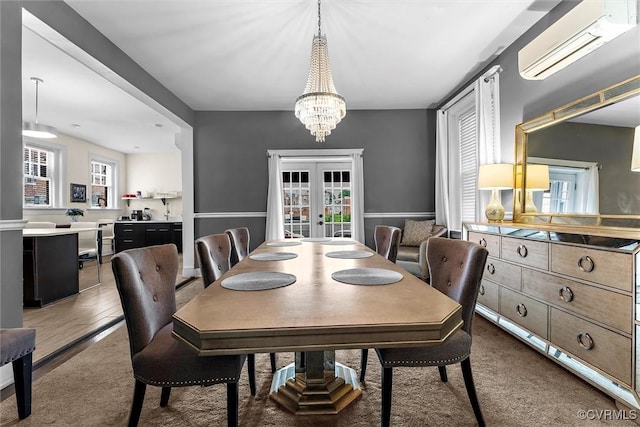 dining room featuring healthy amount of natural light, a chandelier, french doors, and a wall unit AC