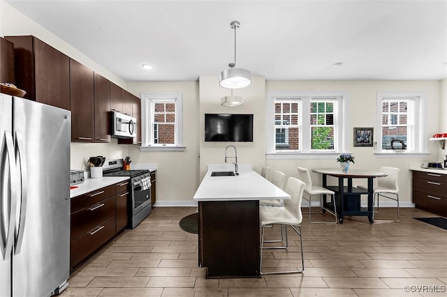 kitchen featuring stainless steel appliances, a sink, a kitchen breakfast bar, and light countertops